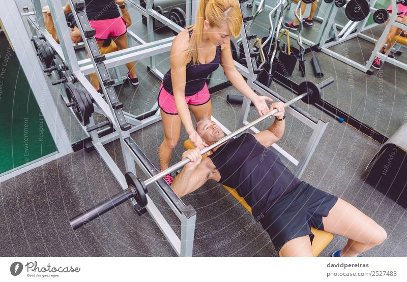 Frauentrainerin hilft dem Mann beim Bankdrücken-Training Sport Schule Erwachsene Freundschaft Fitness authentisch stark Mädchen Personal Trainerin Muskulatur