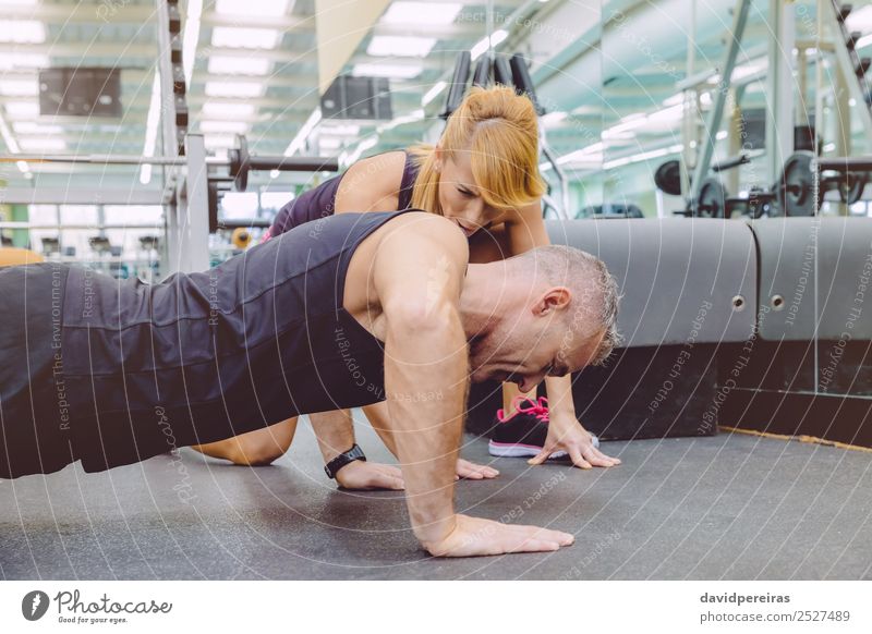 Personal Trainer, der den Muskelmann beim Liegestütz-Training fördert. Lifestyle Körper Freizeit & Hobby Sport Mensch Frau Erwachsene Mann Freundschaft Fitness