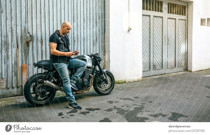 Biker suchen mobiles Sitzen auf dem Motorrad Lifestyle Stil Ausflug PDA Mensch Mann Erwachsene Straße Fahrzeug sitzen warten authentisch retro schwarz