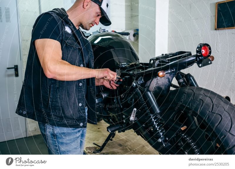 Motorradmechaniker beim Wechseln einer Sicherung Lifestyle Stil Arbeit & Erwerbstätigkeit Mensch Mann Erwachsene Fahrzeug Jeanshose authentisch retro schwarz