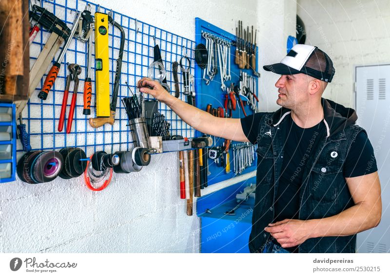 Mechaniker in seiner Werkstatt mit Werkzeugaufnahme Arbeit & Erwerbstätigkeit Hammer Motor Mensch Mann Erwachsene Fahrzeug Motorrad Business Werkzeugtafel