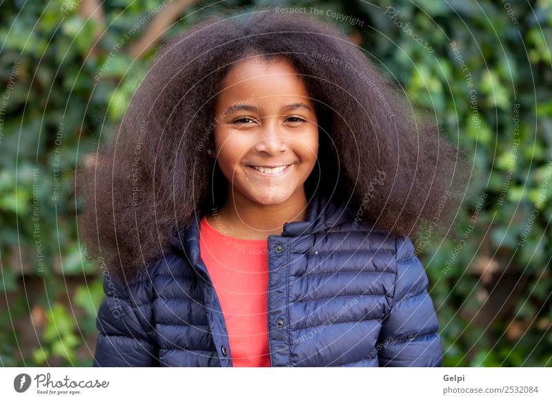 Hübsches Mädchen mit langem Afrohaar. Glück schön Gesicht Winter Garten Kind Mensch Frau Erwachsene Kindheit Park Mantel brünett Afro-Look Lächeln Fröhlichkeit