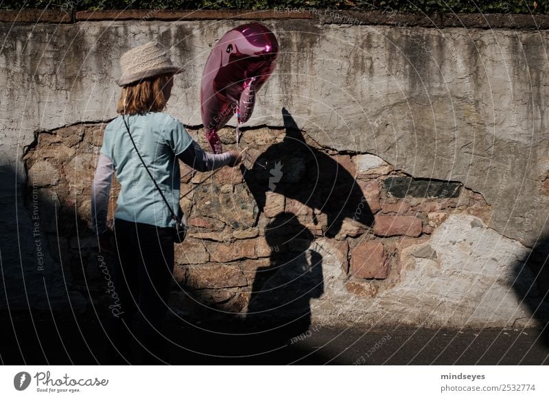 Mädchen mit Delfin-Luftballon wirft einen Schatten an die Mauer Spielen Jahrmarkt Mensch feminin Kindheit 1 Wand Hut Delphine Spielzeug beobachten Blick