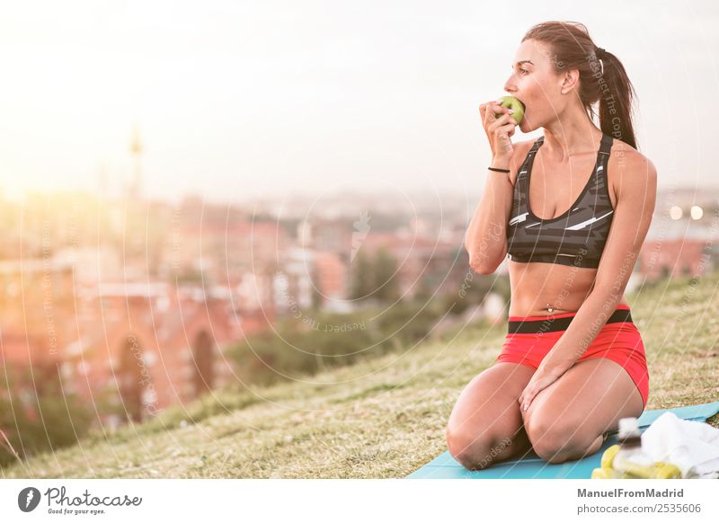 athletische Frau beim Essen eines Apfels Frucht Lifestyle schön Körper Wellness Sommer Sport Joggen Mensch Erwachsene Natur Park Fitness sitzen grün Athlet jung