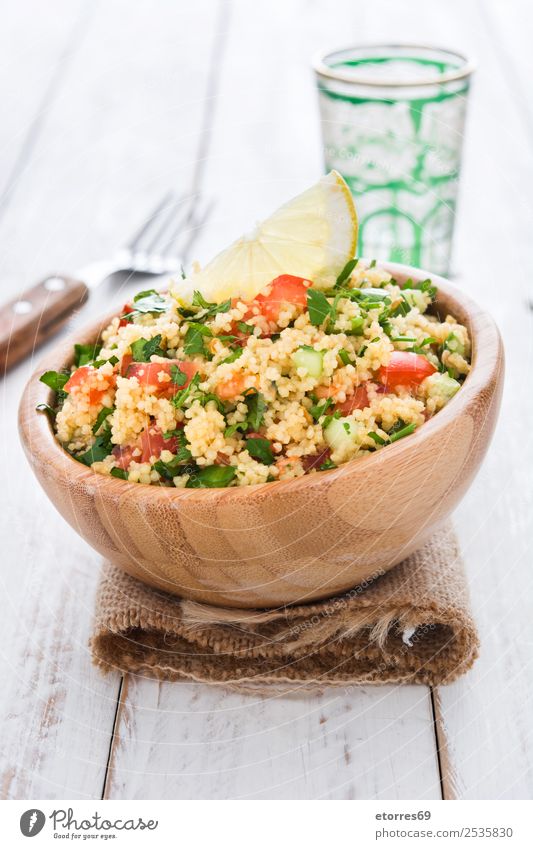 Tabbouleh-Salat mit Couscous auf weißem Holz. Tisch Salatbeilage Gemüse Tomate Gurke Salatgurke Petersilie Minze Vegane Ernährung Vegetarische Ernährung