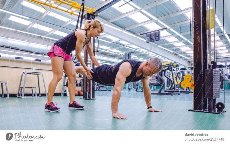 Personal Trainer, der den Mann im Suspensionstraining unterrichtet. Lifestyle schön Körper Sport Arbeit & Erwerbstätigkeit Frau Erwachsene Fitness authentisch