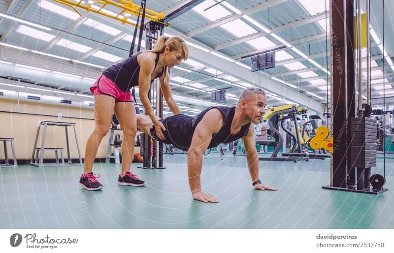 Personal Trainer, der den Mann im Suspensionstraining unterrichtet. Lifestyle schön Körper Sport Arbeit & Erwerbstätigkeit Frau Erwachsene Fitness authentisch