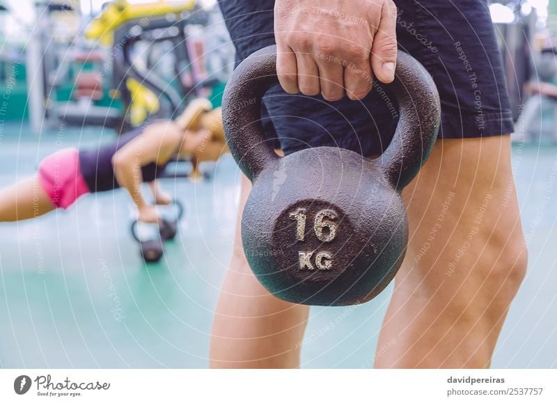 Mann hält Kugelglocke und Frau macht Liegestütze in Kugelglocken. Lifestyle Körper Sport Erwachsene Hand Fitness authentisch muskulös stark schwarz Kraft