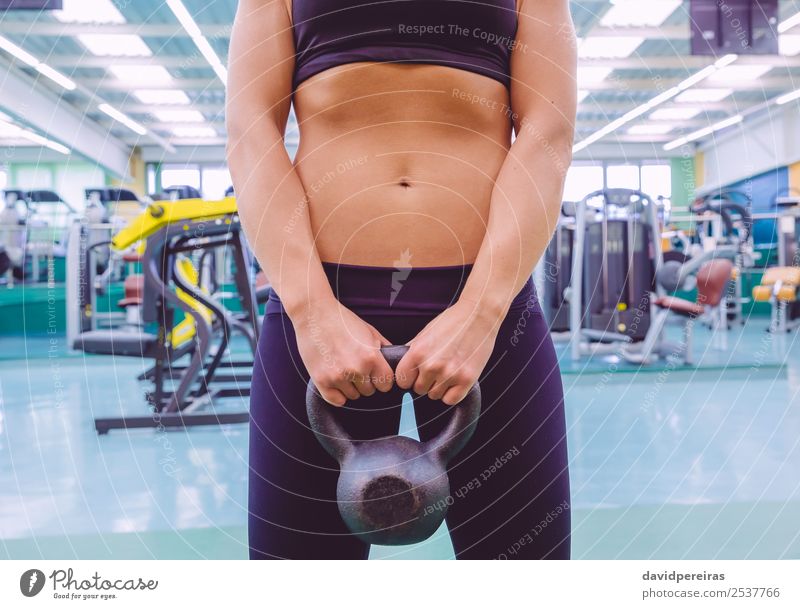 Frau mit schmaler Taille und schwarzer Sportbekleidung mit Kugelkopf. Diät schön Körper Mensch Erwachsene Fitness authentisch dünn Erotik Kraft Kettlebell