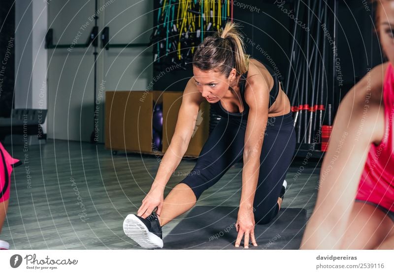 Frau, die ihre Beine in einer Fitness-Klasse dehnt. Lifestyle Glück schön Körper Freizeit & Hobby Sport Schule Mensch Erwachsene Arme Menschengruppe Zopf