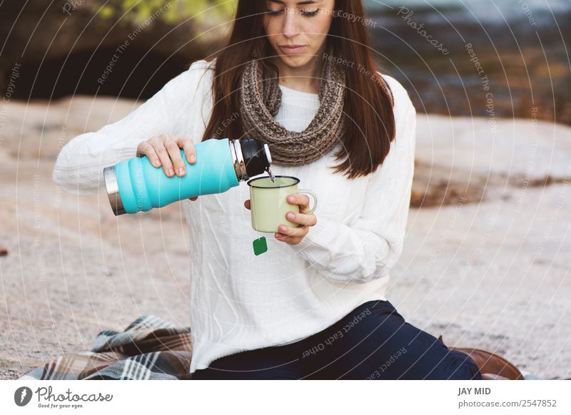 Junge Frau, die in der Nähe des Wasserfalls sitzt, Lebensmittel Frühstück Heißgetränk Tee Lifestyle Erholung Freizeit & Hobby Ferien & Urlaub & Reisen Mensch