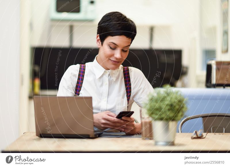 Junge Frau mit sehr kurzem Haarschnitt und Smartphone Lifestyle Stil Glück schön Haare & Frisuren Haus Schreibtisch Arbeit & Erwerbstätigkeit Business Telefon