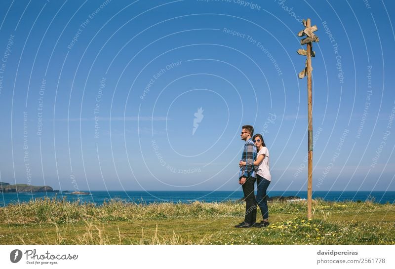 Paar, das von einem Wegweiser umarmt wird. Ferien & Urlaub & Reisen Abenteuer Freiheit Meer Mensch Frau Erwachsene Mann Natur Landschaft Gras Wiese Küste