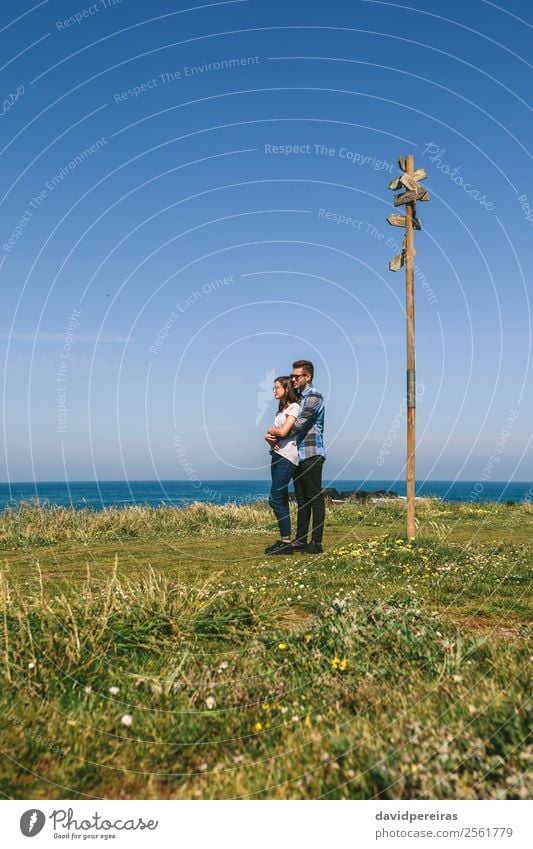 Paar, das von einem Wegweiser umarmt wird. ruhig Ferien & Urlaub & Reisen Abenteuer Freiheit Meer Mensch Frau Erwachsene Mann Landschaft Gras Wiese Küste