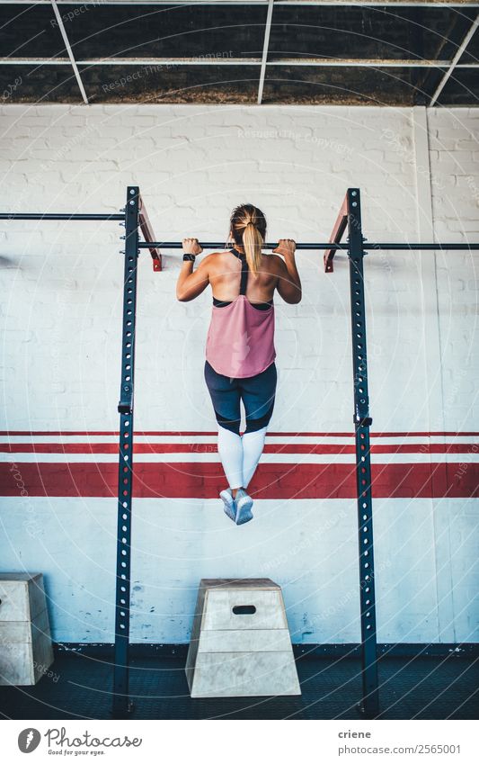 junge kaukasische Frau beim Pull-up in der Turnhalle Körper Sport Mensch Erwachsene Fitness muskulös stark Kraft Training Klimmzüge Athlet üben