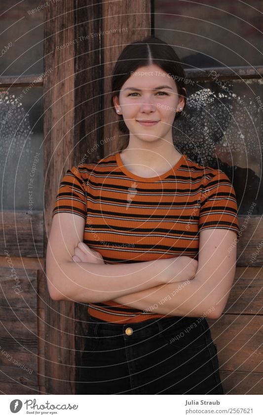 Junge Frau Holztür Glas feminin Jugendliche 1 Mensch 13-18 Jahre Fenster Tür T-Shirt Hose brünett langhaarig Zopf Lächeln stehen Coolness schön retro braun