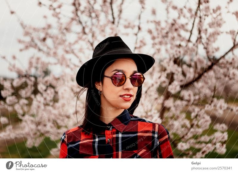 Mädchen Stil Glück schön Gesicht Garten Mensch Frau Erwachsene Natur Baum Blume Blüte Park Mode Sonnenbrille Hut brünett Lächeln Fröhlichkeit frisch lang