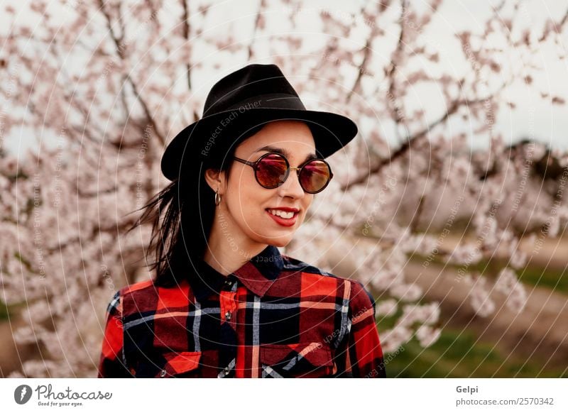 Mädchen Stil Glück schön Gesicht Garten Mensch Frau Erwachsene Natur Baum Blume Blüte Park Mode Sonnenbrille Hut brünett Lächeln Fröhlichkeit frisch lang