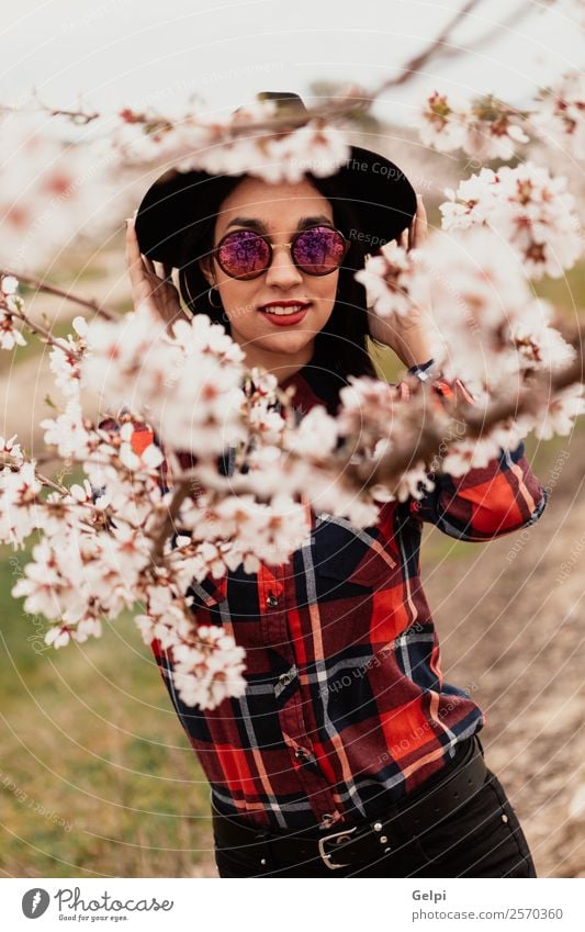 Mädchen Stil Glück schön Gesicht Garten Mensch Frau Erwachsene Natur Baum Blume Blüte Park Mode Sonnenbrille Hut brünett Lächeln Fröhlichkeit frisch lang