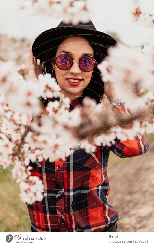 Mädchen Stil Glück schön Gesicht Garten Mensch Frau Erwachsene Natur Baum Blume Blüte Park Mode Sonnenbrille Hut brünett Lächeln Fröhlichkeit frisch lang