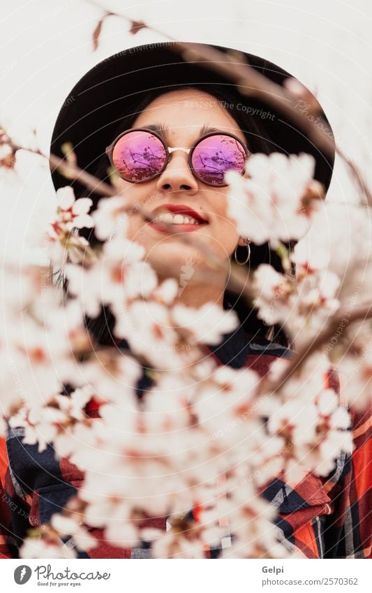 Mädchen Stil Glück schön Gesicht Garten Mensch Frau Erwachsene Natur Baum Blume Blüte Park Mode Sonnenbrille Hut brünett Lächeln Fröhlichkeit frisch lang