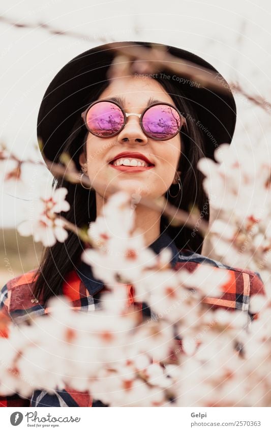 Mädchen Stil Glück schön Gesicht Garten Mensch Frau Erwachsene Natur Baum Blume Blüte Park Mode Sonnenbrille Hut brünett Lächeln Fröhlichkeit frisch lang