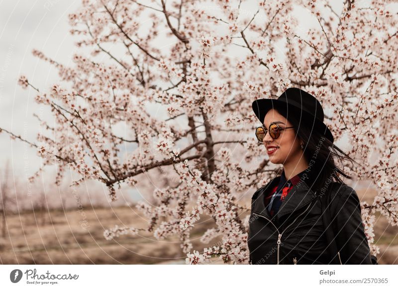 Mädchen Stil Glück schön Gesicht Garten Mensch Frau Erwachsene Natur Baum Blume Blüte Park Mode Jacke Leder Sonnenbrille brünett Lächeln Fröhlichkeit frisch