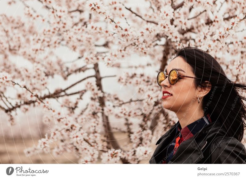 Mädchen Stil Glück schön Gesicht Garten Mensch Frau Erwachsene Natur Baum Blume Blüte Park Mode Jacke Leder Sonnenbrille brünett Lächeln Fröhlichkeit frisch