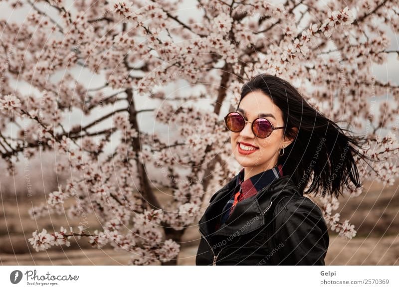 Mädchen Stil Glück schön Gesicht Garten Mensch Frau Erwachsene Natur Baum Blume Blüte Park Mode Jacke Leder Sonnenbrille brünett Lächeln Fröhlichkeit frisch