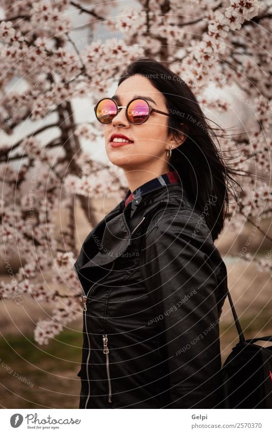 Mädchen Stil Glück schön Gesicht Garten Mensch Frau Erwachsene Natur Baum Blume Blüte Park Mode Jacke Leder Sonnenbrille brünett Lächeln Fröhlichkeit frisch