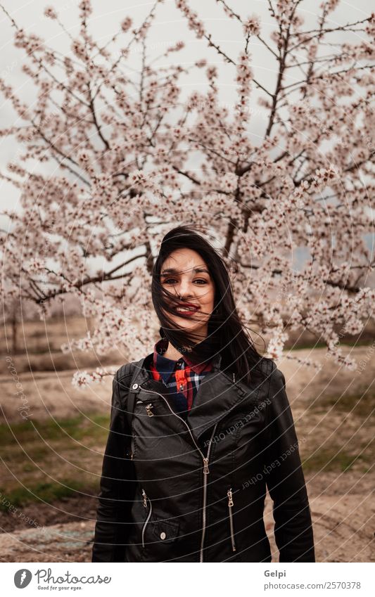 Mädchen Stil Glück schön Gesicht Garten Mensch Frau Erwachsene Natur Baum Blume Blüte Park Mode Jacke Leder brünett Lächeln Fröhlichkeit frisch lang natürlich