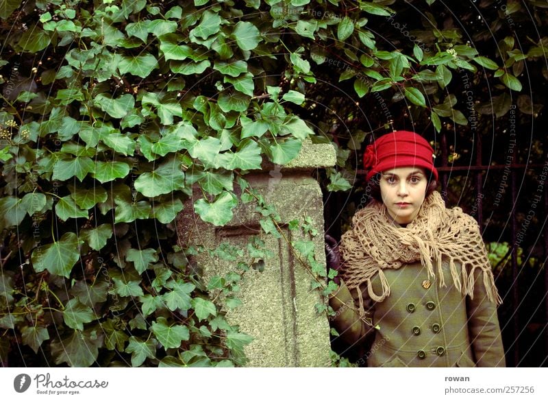 ernst Mensch feminin Junge Frau Jugendliche 1 Sträucher Blatt Mauer Wand Hut rot grün Efeu bewachsen Tor Garten Gartentor alt retro Mantel Blick Handschuhe