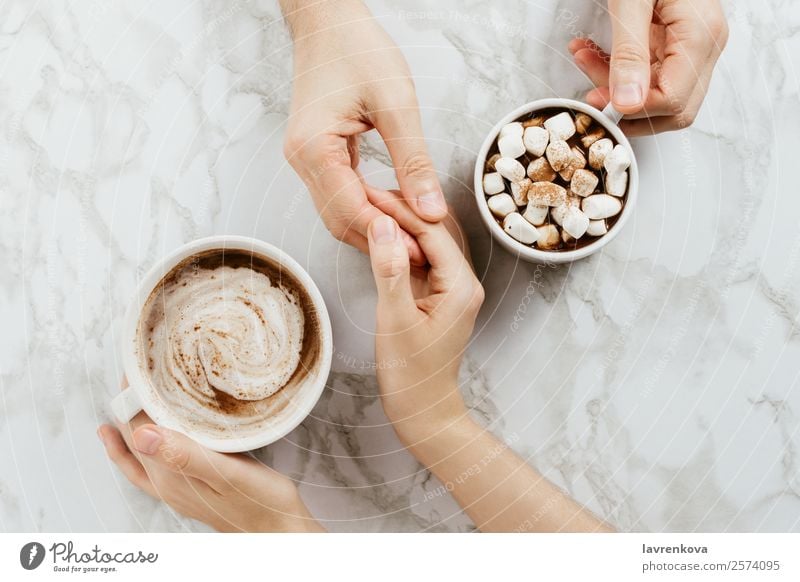 Frau und Mann halten Händchen und zwei Tassen vegane Kakaos. Finger Zusammensein Marmor Morgen Tisch Frühstück Ernährung Hygge Verabredung Herbst Paar Romantik