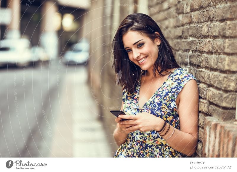 Lächelnde junge Frau, die ihr Smartphone im Freien benutzt. Lifestyle Stil Glück schön Haare & Frisuren Telefon PDA Technik & Technologie Mensch feminin