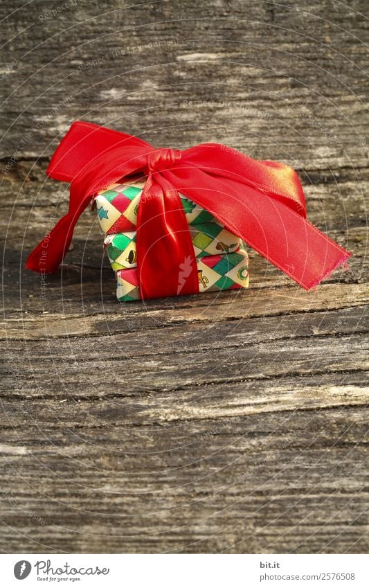 bunte Weihnachtspäckchen verpackt mit Weihnachtspapier mit roter Schleife, auf rustikalem Holz. Weihnachtsgeschenke, liegen hübsch dekoriert mit Band auf Holztisch. Viele Weihnachtspäckchen mit Geschenkpapier mit Weihnachtsmotiv. Konzept Geschenke Advent.