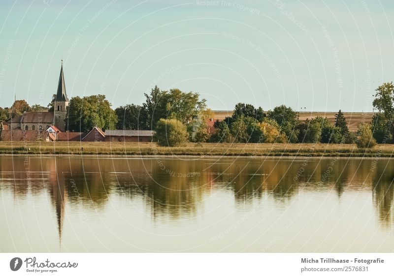 Dorf am See Natur Landschaft Wasser Himmel Wolkenloser Himmel Sonnenlicht Herbst Schönes Wetter Baum Sträucher Kirchturm Haus Kirche Erholung glänzend leuchten