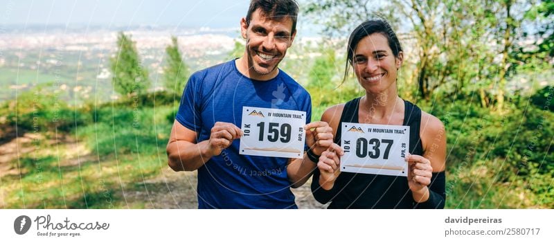 Mann und Frau zeigen ihre Trail-Rennnummer an. Lifestyle Glück Sport Erfolg Mensch Erwachsene Freundschaft Paar Natur Wald Wege & Pfade Lächeln stehen