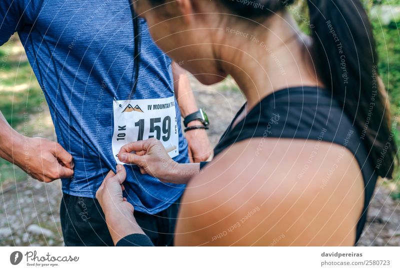 Trail-Athletin, die ihrer Partnerin die Startnummer zuweist. Lifestyle Sport Mensch Frau Erwachsene Mann Freundschaft Paar Natur Wald Wege & Pfade stehen