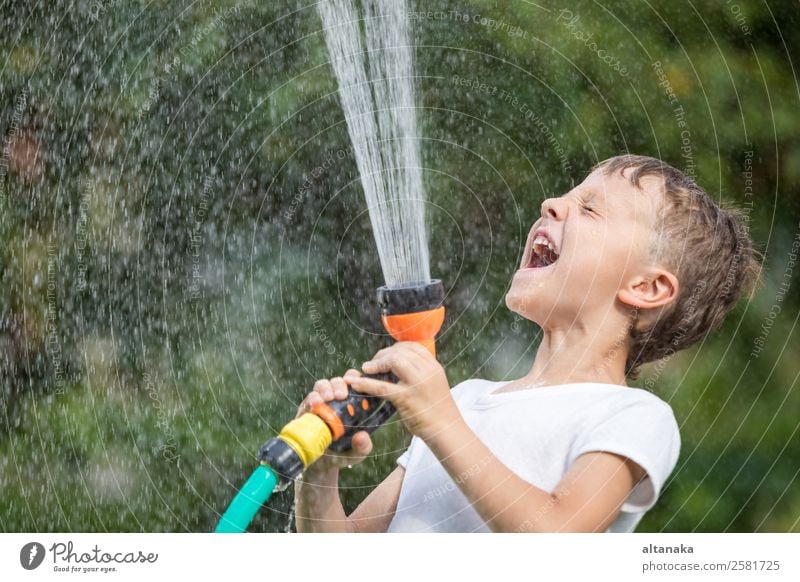 Glücklicher kleiner Junge, der Wasser aus einem Schlauch gießt. Kind hat Spaß im Freien. Freude Freizeit & Hobby Spielen Ferien & Urlaub & Reisen Freiheit