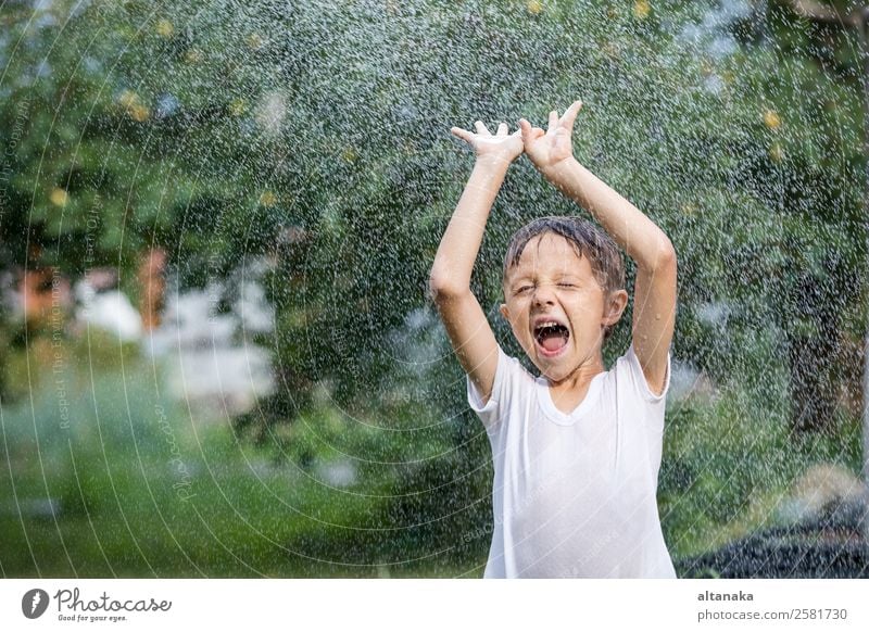 Glücklicher kleiner Junge, der Wasser aus einem Schlauch gießt. Freude Freizeit & Hobby Spielen Ferien & Urlaub & Reisen Freiheit Camping Sommer Haus Garten