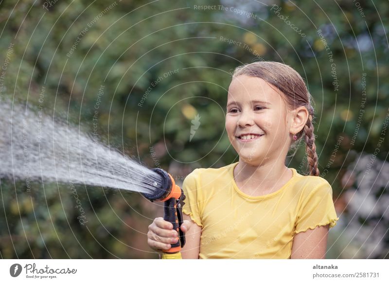 Glückliches kleines Mädchen, das Wasser aus einem Schlauch gießt. Freude Freizeit & Hobby Spielen Ferien & Urlaub & Reisen Freiheit Camping Sommer Haus Garten