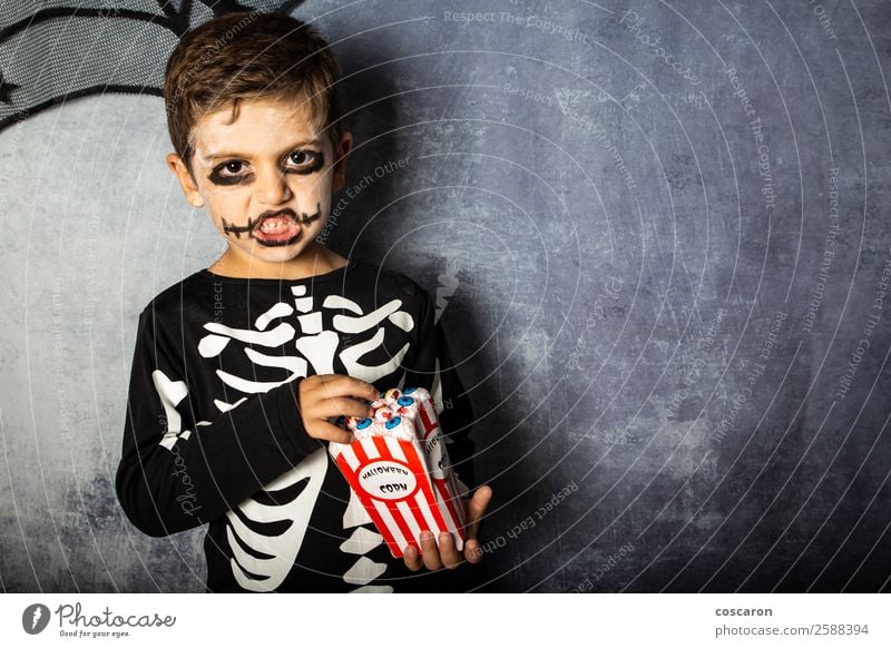 Kleines Kind in einem Skelettkostüm isst an Halloween gefälschte Augen. Freude Glück Gesicht Schminke Feste & Feiern Karneval Jahrmarkt Mensch Kleinkind Junge