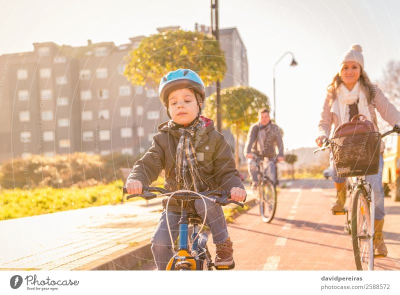 Glückliche Familie mit einem Kind, das Fahrräder durch die Stadt fährt. Lifestyle Erholung Freizeit & Hobby Ferien & Urlaub & Reisen Sonne Winter Sport Junge