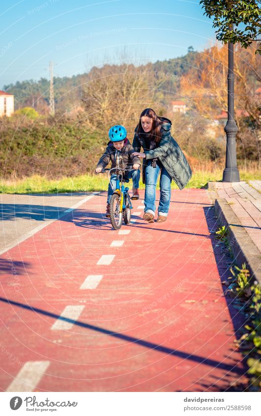 Mutter bringt ihrem Sohn bei, Fahrrad zu fahren. Lifestyle Freude Glück Freizeit & Hobby Spielen Sonne Winter Sport Erfolg Fahrradfahren Kind Schule Junge Frau