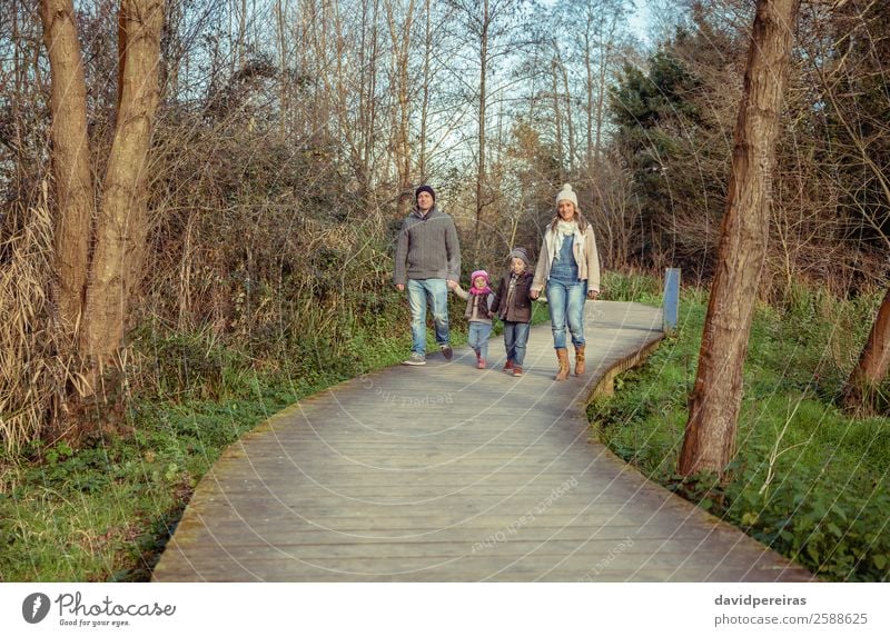 Glückliche Familie, die gemeinsam im Wald Hand in Hand geht. Lifestyle schön Freizeit & Hobby Ferien & Urlaub & Reisen Winter Kind Mensch Junge Frau Erwachsene