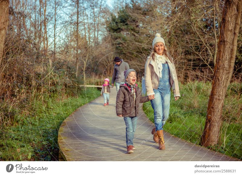 Glückliche Familie, die gemeinsam über einen Holzweg geht. Lifestyle Freude Freizeit & Hobby Winter Kind Junge Frau Erwachsene Mann Eltern Mutter Vater