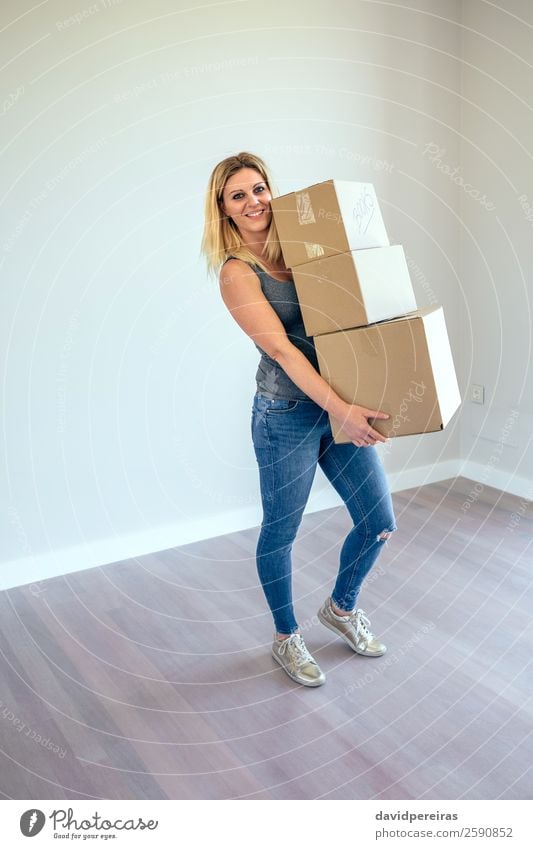 Frau mit Umzugskisten Glück schön Haus Umzug (Wohnungswechsel) Wohnzimmer Mensch Erwachsene Buch Jeanshose Turnschuh blond Kasten Lächeln stehen tragen