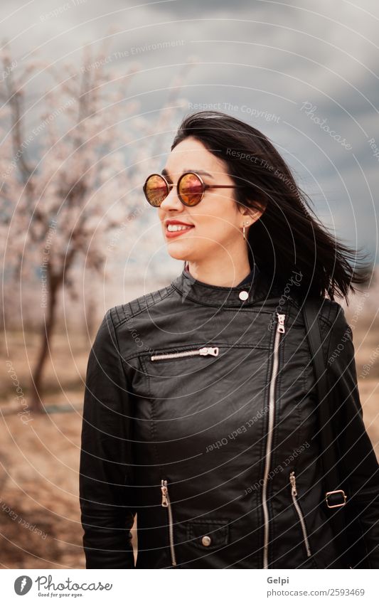 Brünettes Mädchen Stil Glück schön Gesicht Garten Mensch Frau Erwachsene Natur Baum Blume Blüte Park Mode Jacke Leder Sonnenbrille brünett Lächeln Fröhlichkeit