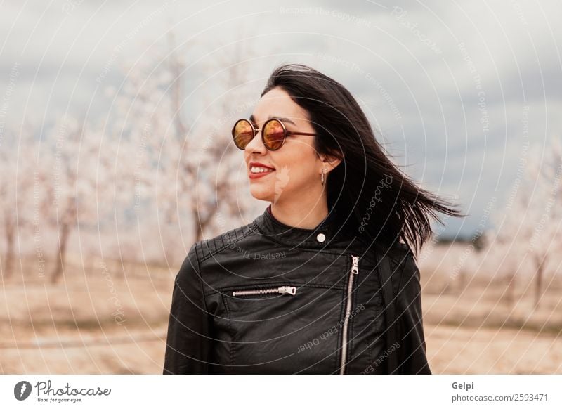 Brünettes Mädchen Stil Glück schön Gesicht Garten Mensch Frau Erwachsene Natur Baum Blume Blüte Park Mode Jacke Leder Sonnenbrille brünett Lächeln Fröhlichkeit