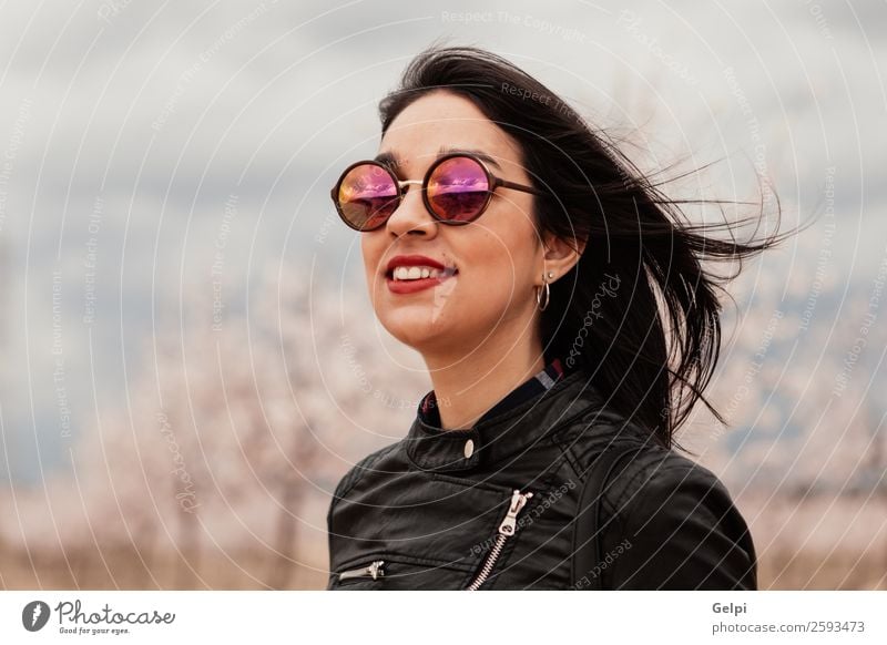 Hübsches brünettes Mädchen Stil Glück schön Gesicht Garten Mensch Frau Erwachsene Natur Baum Blume Blüte Park Mode Jacke Leder Sonnenbrille Lächeln Fröhlichkeit